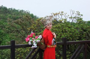 shutterstock_59180779 Hunan, A Hunan lady in traditional attire stand in front a beautiful mountain range